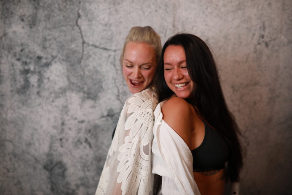 Two Women posing in front of a backdrop at a Denver event.