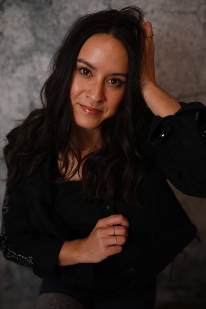 Woman posing in front of a backdrop at a Denver event.