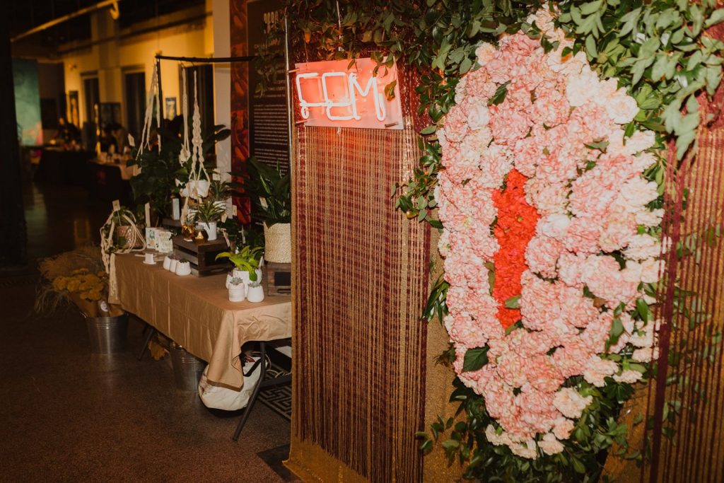 Large wall hanging floral design with a pink neon sign.