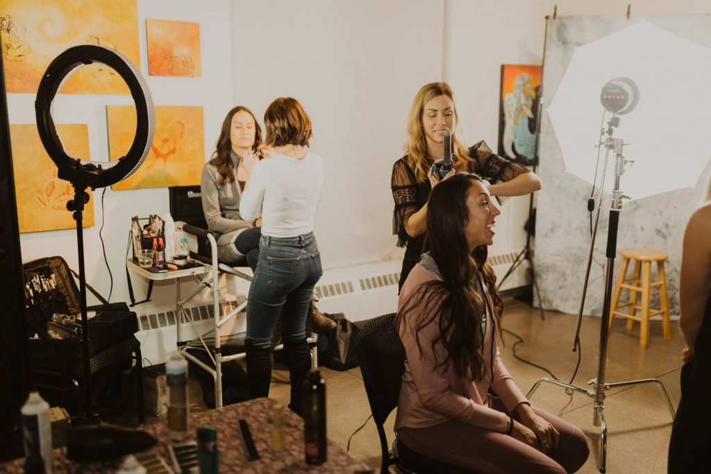 Hair and makeup artist making over two women at an event.