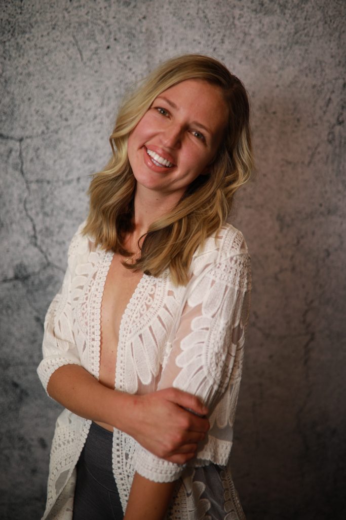 Woman posing in front of a backdrop at a Denver event.