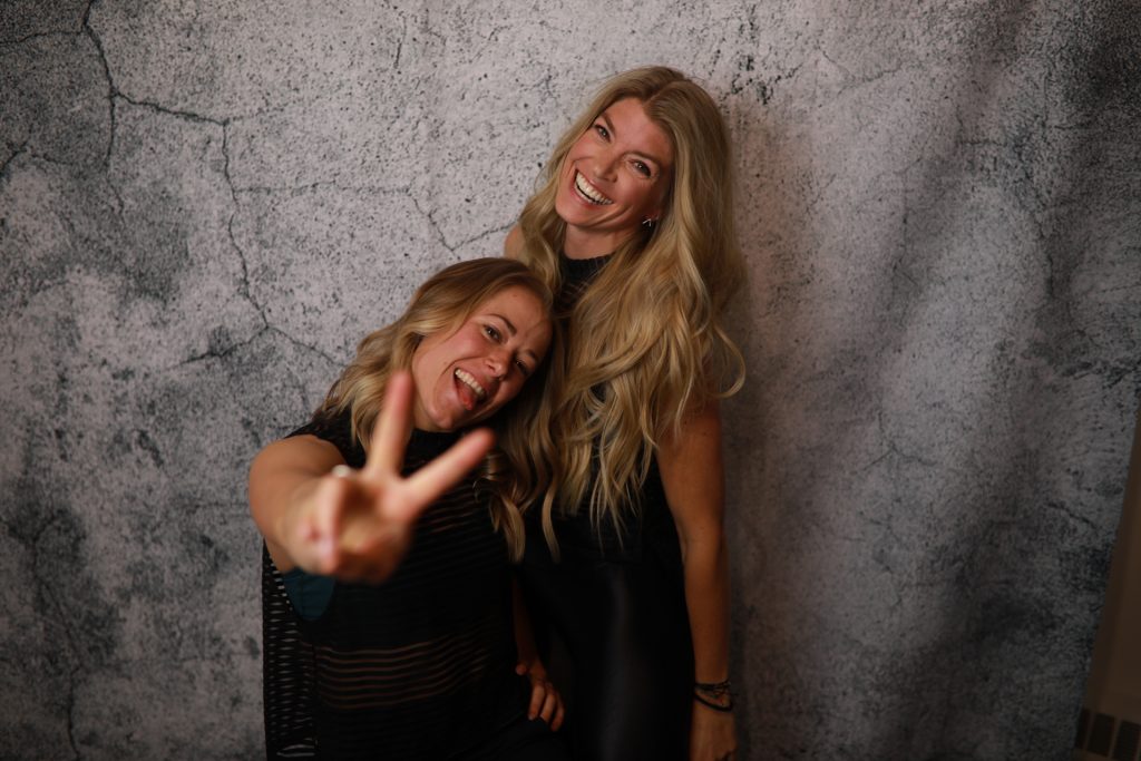 Two Women posing in front of a backdrop at a Denver event.