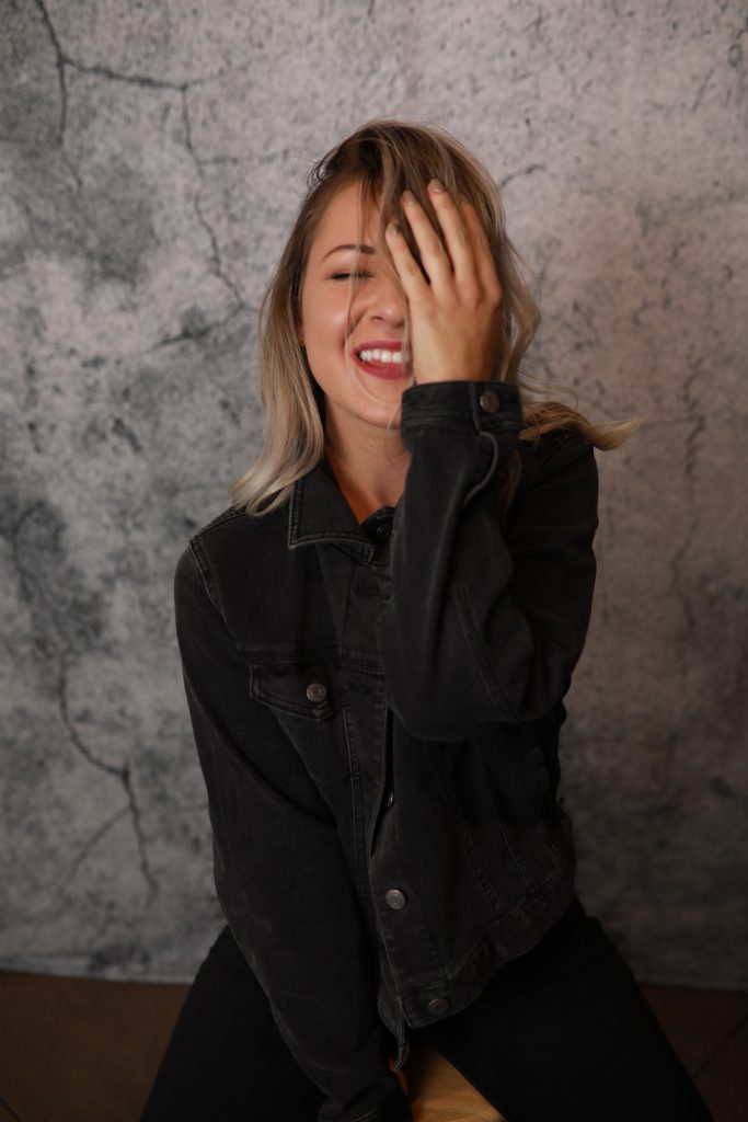 Woman posing in front of a backdrop at a Denver event.