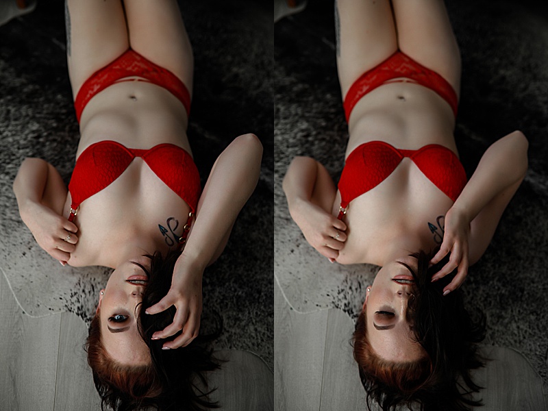 Gallery-of-a-Woman-wearing-red-lingerie-laying-on-a-cowhide-rug-with-one-hand-in-her-hair-coving-half-her-face-and-the-other-tugging-on-her-bra-strap-for-boudoir-photos