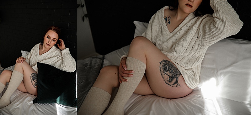 dark-haired-woman-posing-on-a-bed-wearing-a-cream-colored-sweater-and-knee-high-socks