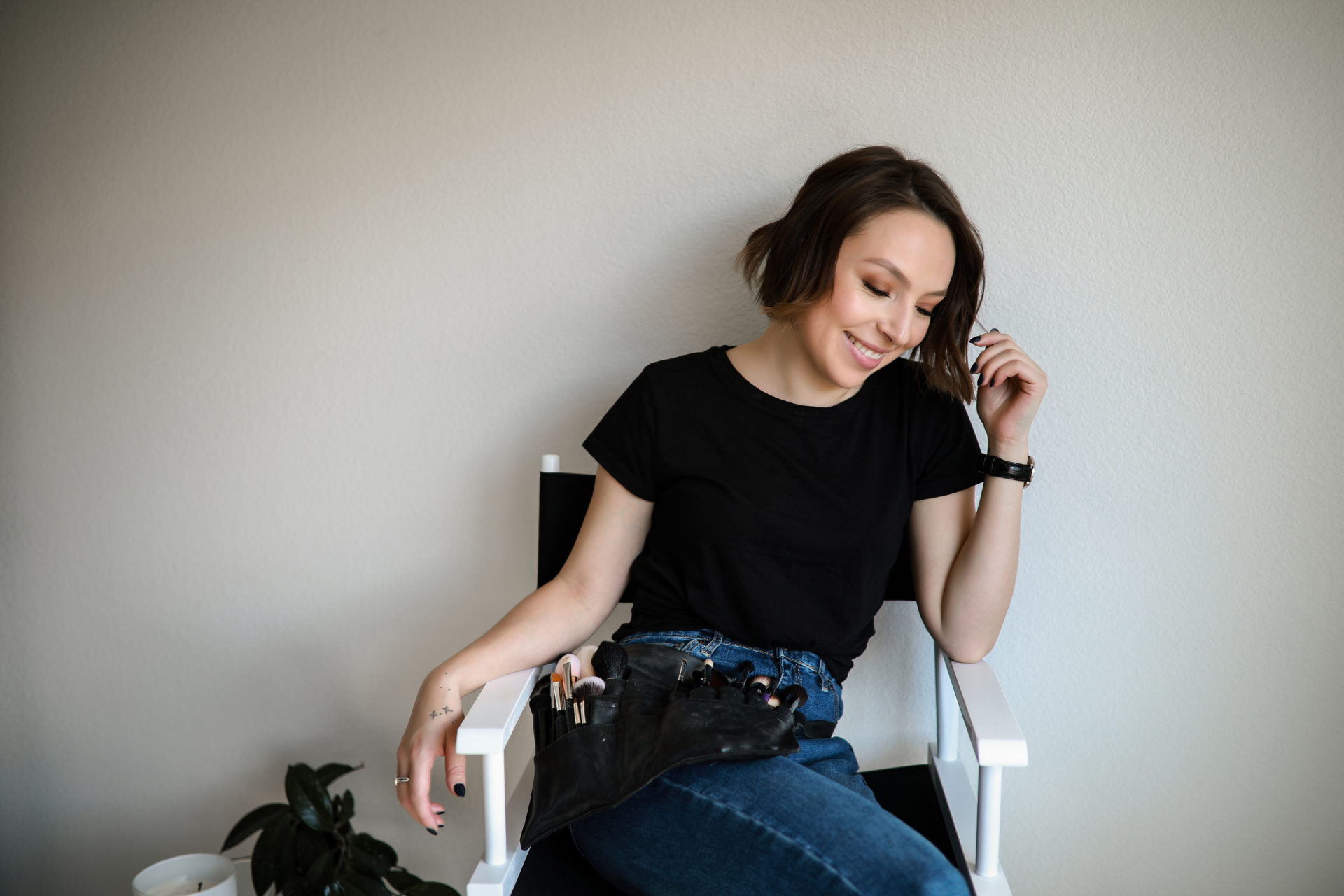 Denver-makeup-artist-posing-on-a-chair-with-their-makeup-belt