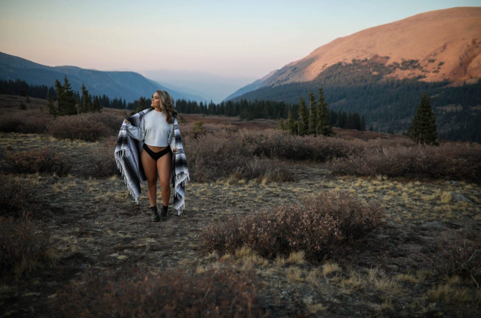 Colorado-boudoir-image-of-a-woman-wrapped-in-a-blanket-standing-at-the-top-of-a-mountain