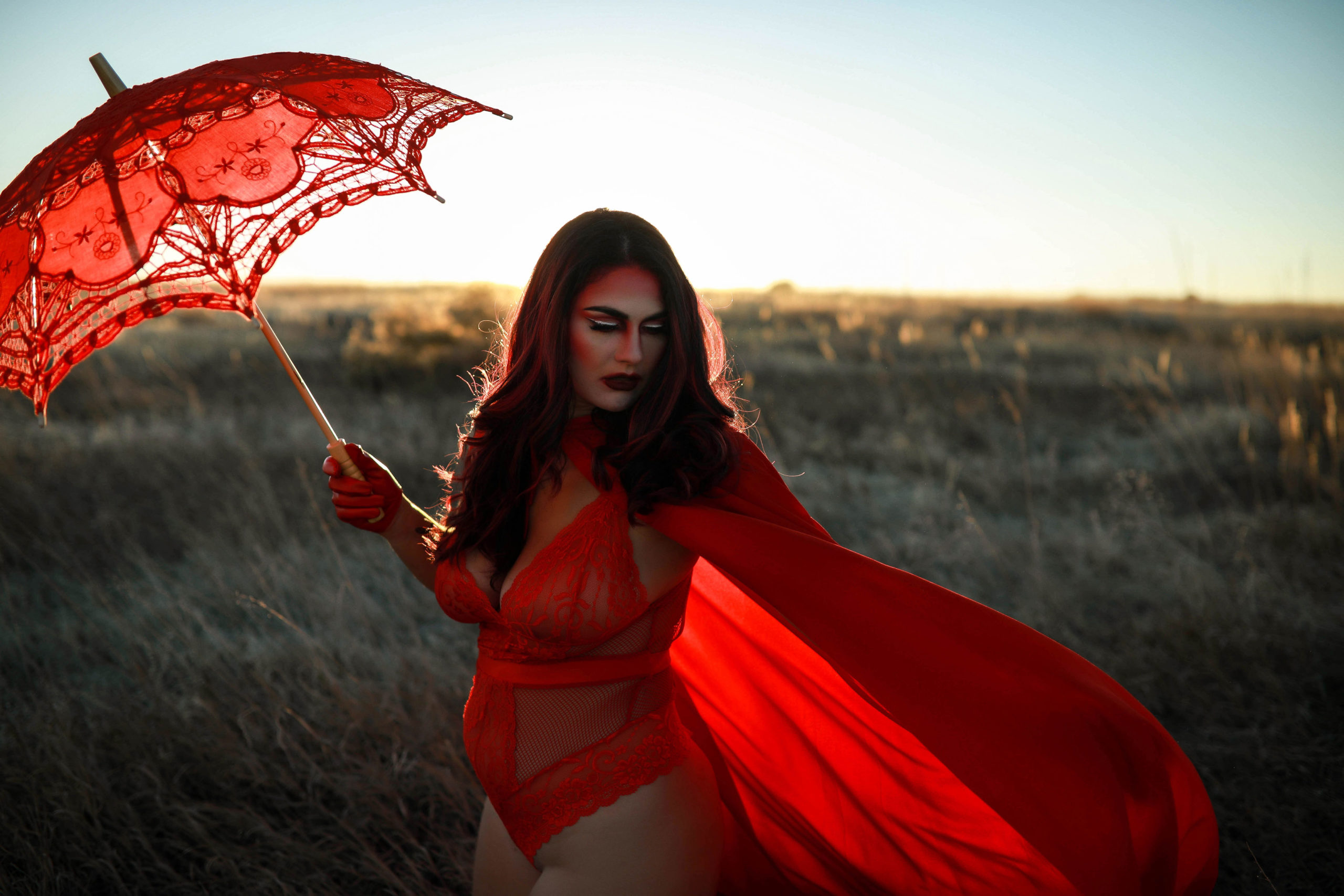 A woman in a red flowing dress and a red parasol