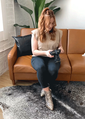 Video-of-woman-sitting-on-a-leather-couch-holding-up-a-camera