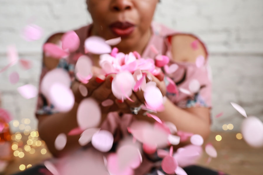 Woman-blowing-pink-confetti-from-her-hands