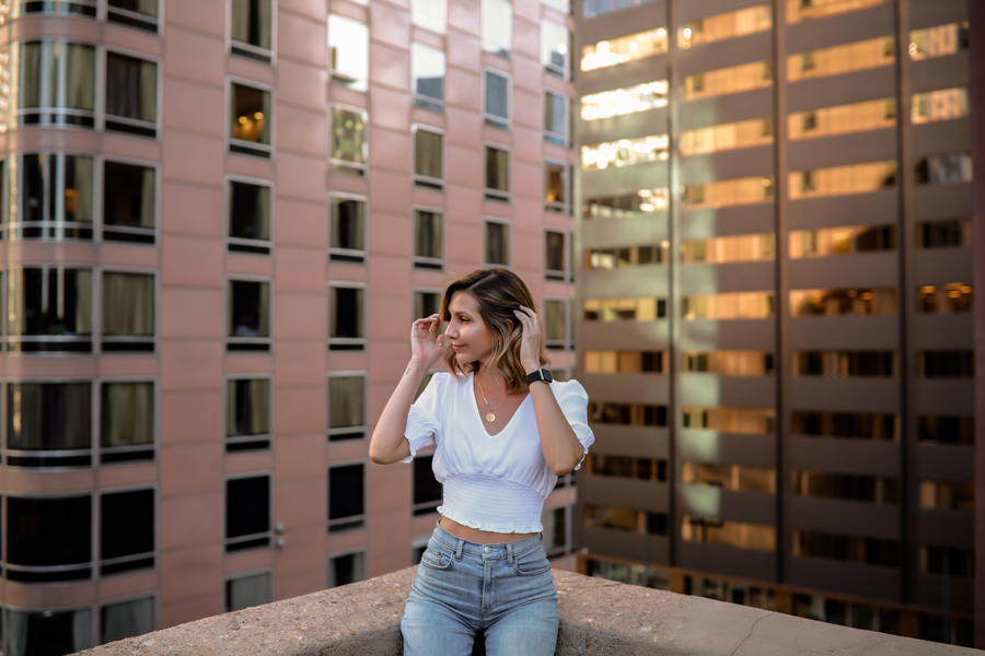 Woman-in-jean-and-white-top-posing-on-the-roof-of-parking-garage-downtown-denver