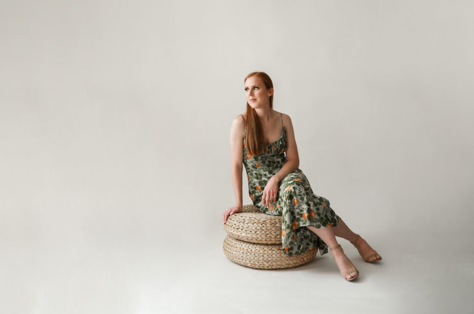 Woman sitting on woven poufs in a Denver studio setting.