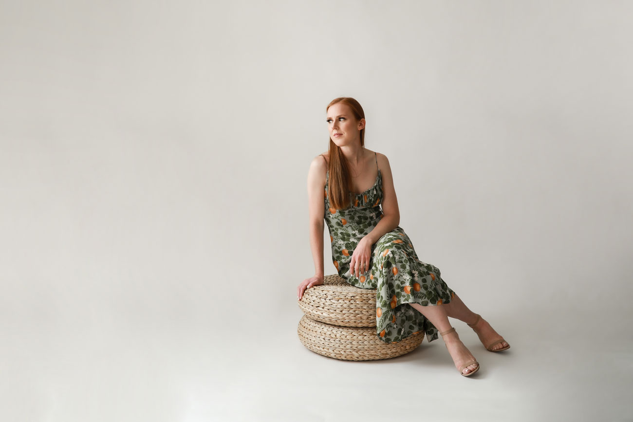 Woman sitting on woven poufs in a Denver studio setting.