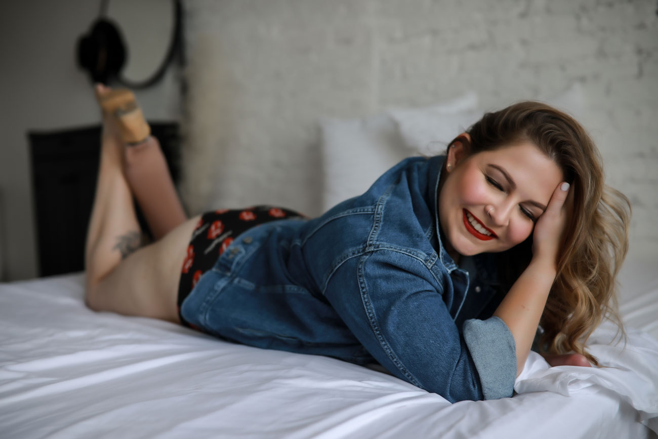 Woman-posing-on-bed-wearing-denim-jacket-for-empowerment-session