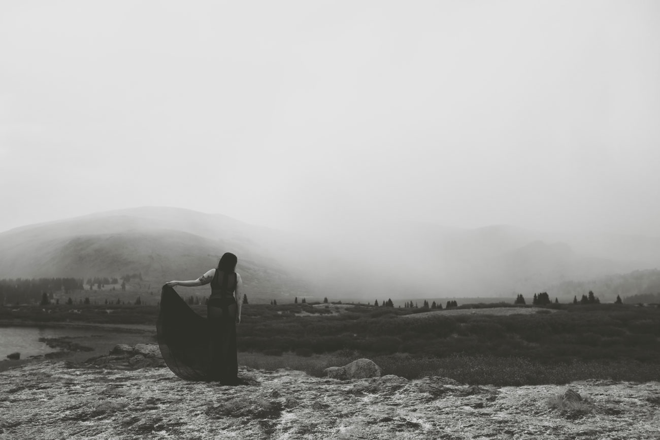 Solitary figure standing in a spooky, misty open landscape with mountains in the background.