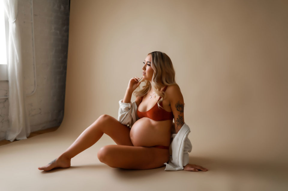 Pregnant woman posing in lingerie and button up stop.