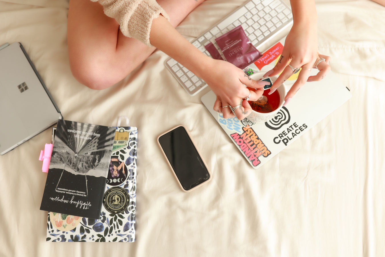 Overhead image of woman working on laptop in bed with a mug of tea.