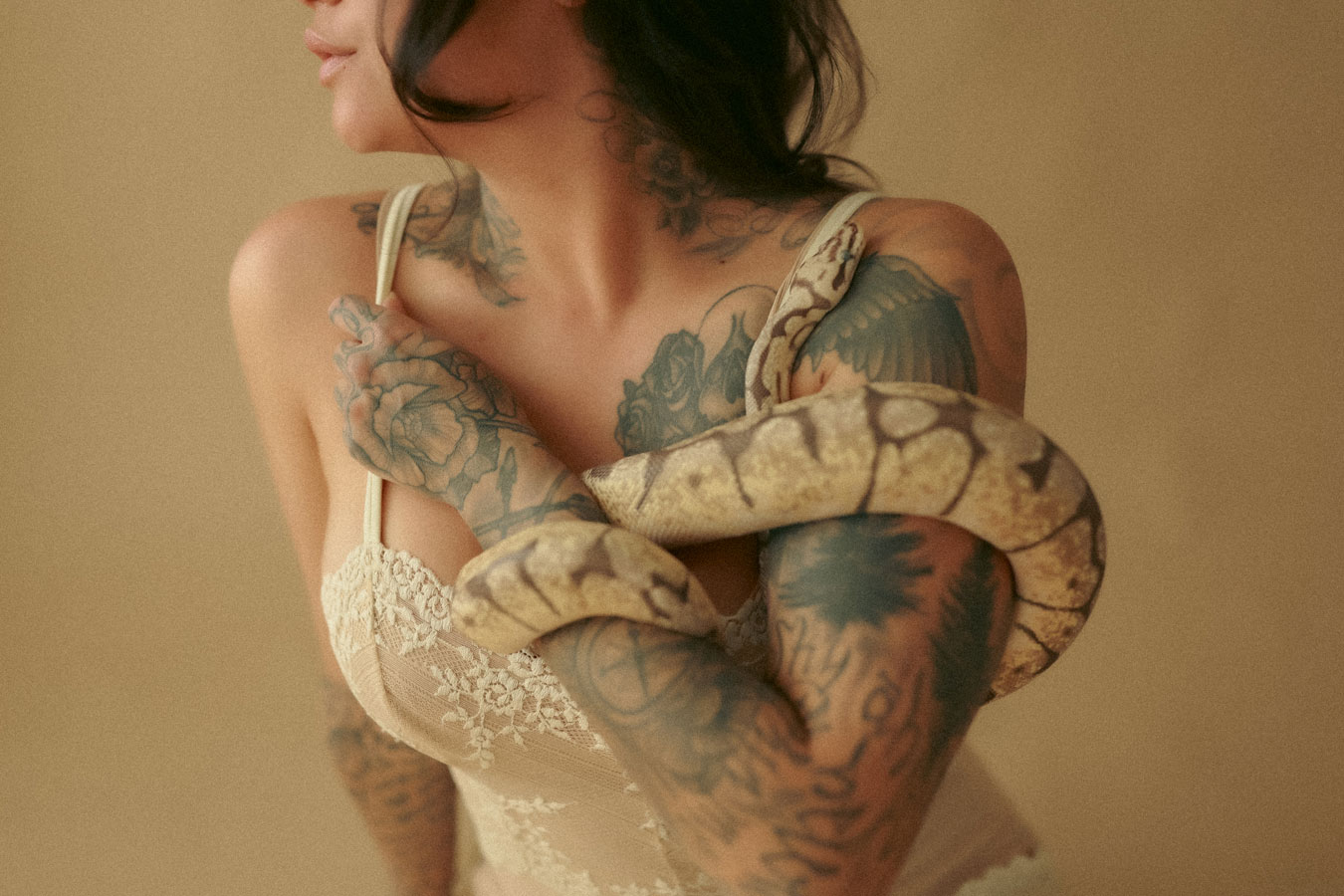 Tattooed woman in lace top with snake wrapped around arm.