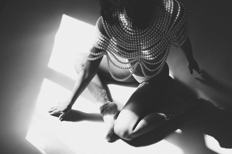 Woman in pearl top sitting on floor in the sun.