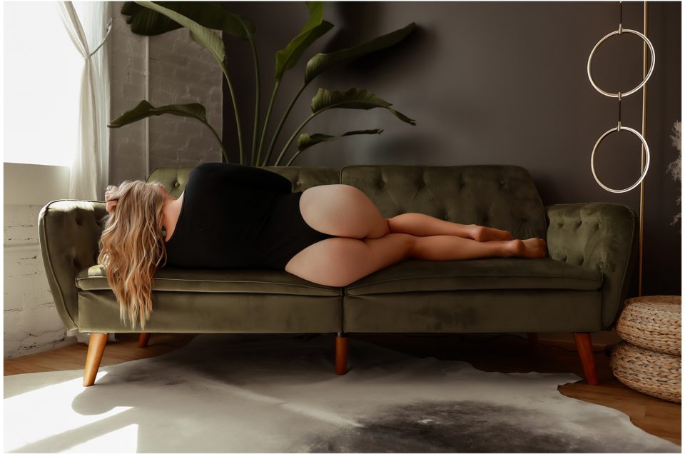 Woman laying on side on couch facing away.