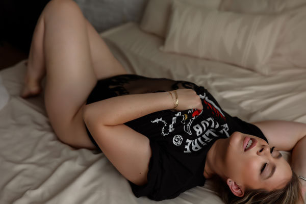 Woman laying on bed with back graphic shirt on.