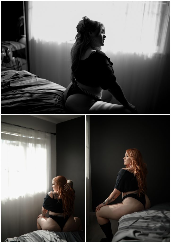 Woman in black crop top sitting on corner of bed in a dark grey bedroom.