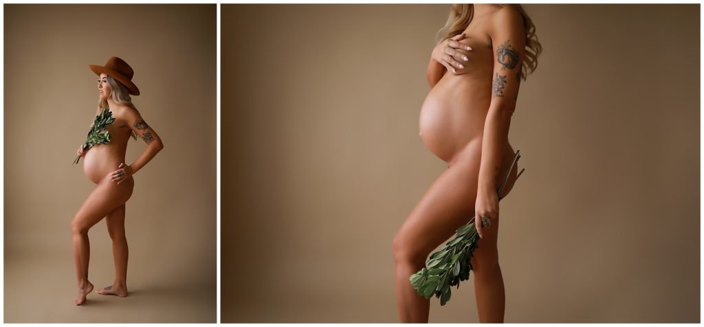 Naked pregnant woman in hat holding green foliage.