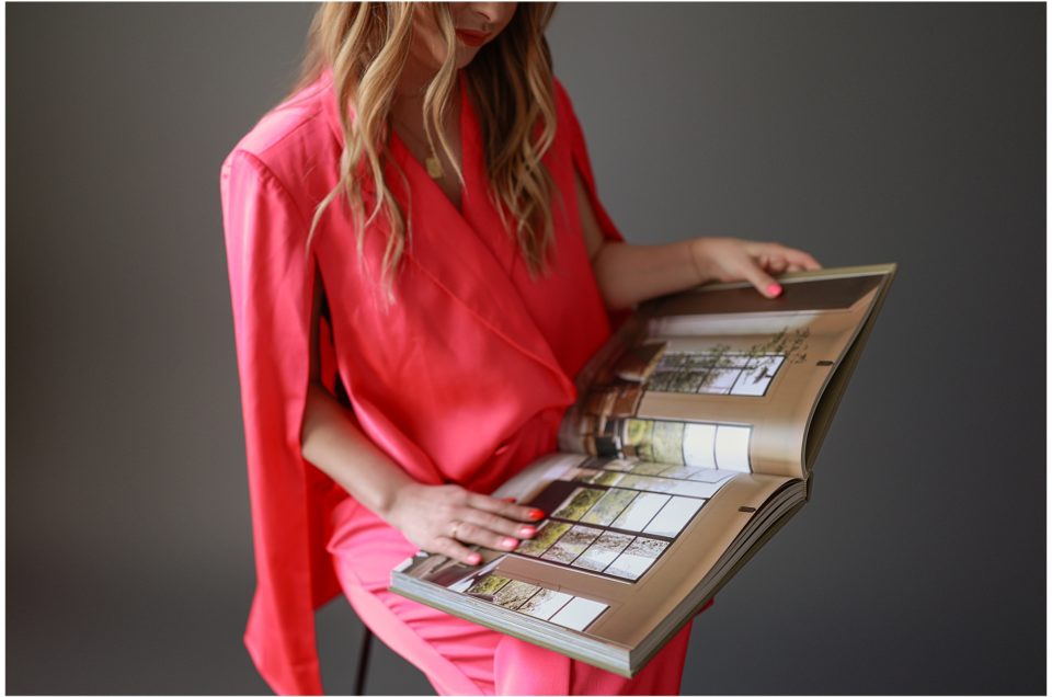 Woman in a pink garment reading a large open "Denver Branding" book.