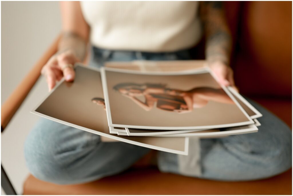 Woman holding maternity photo prints.