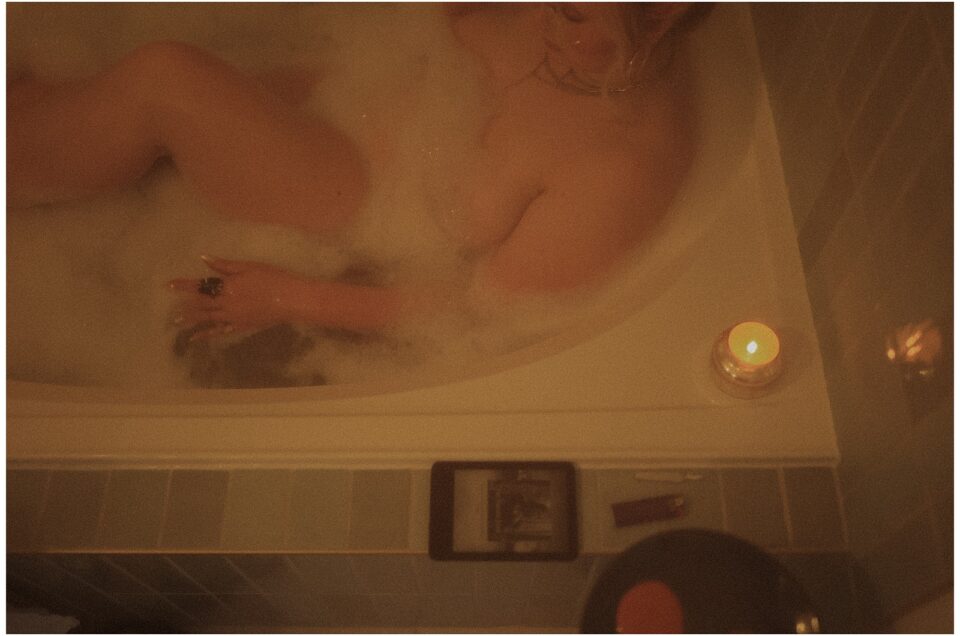A person relaxing in a reverie in a candlelit bubble bath.