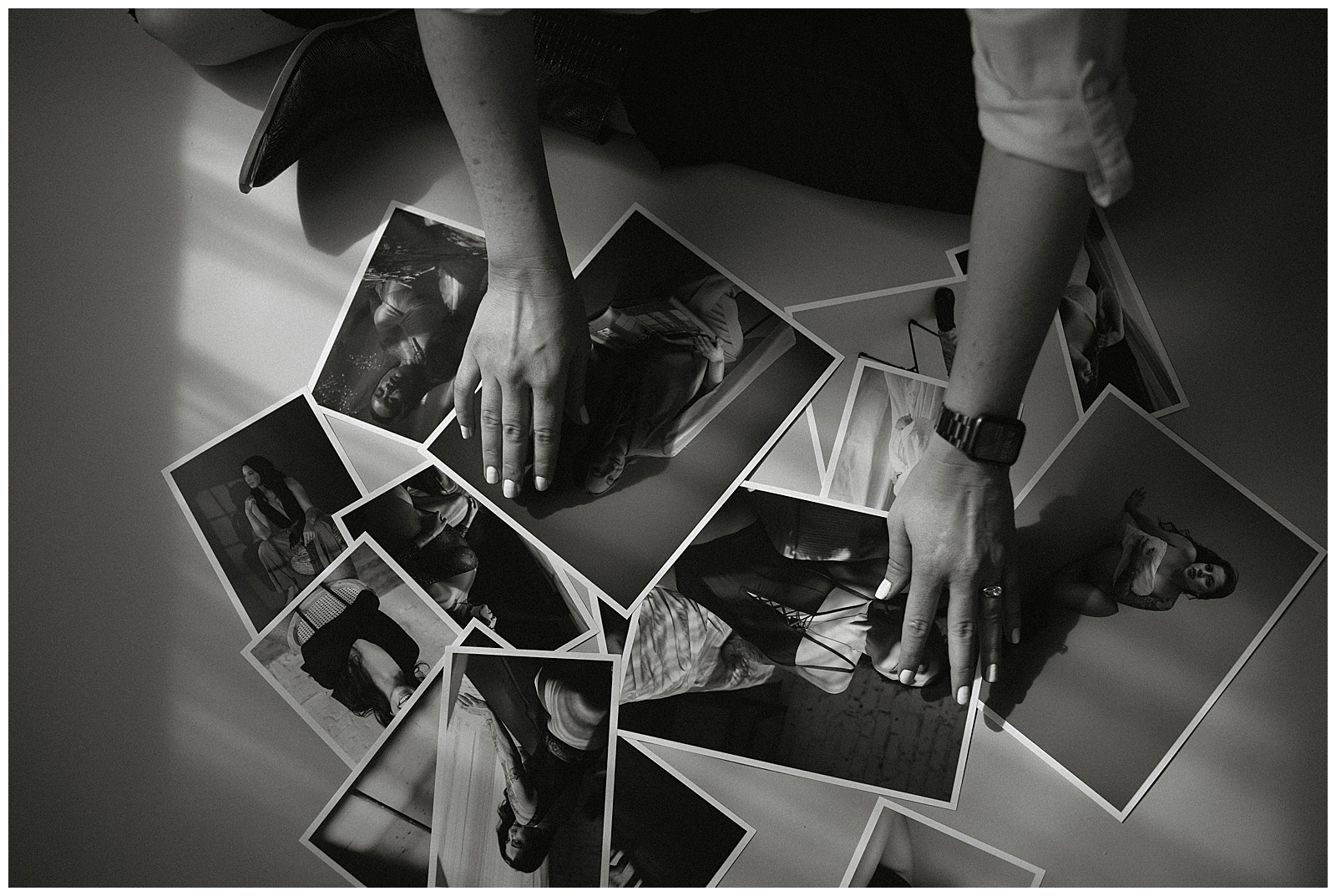 A person with a smartwatch and rings is arranging black and white photographs on a flat surface, showcasing various individuals in different poses. As they carefully place each photo, it’s clear they have many creative ways to work with me.