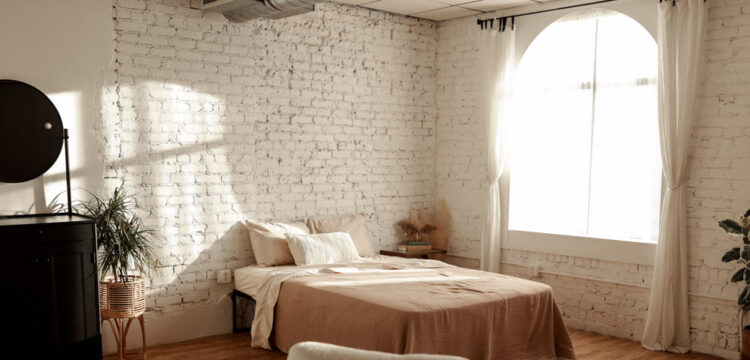 Cozy bedroom with a rustic brick wall and warm natural light.
