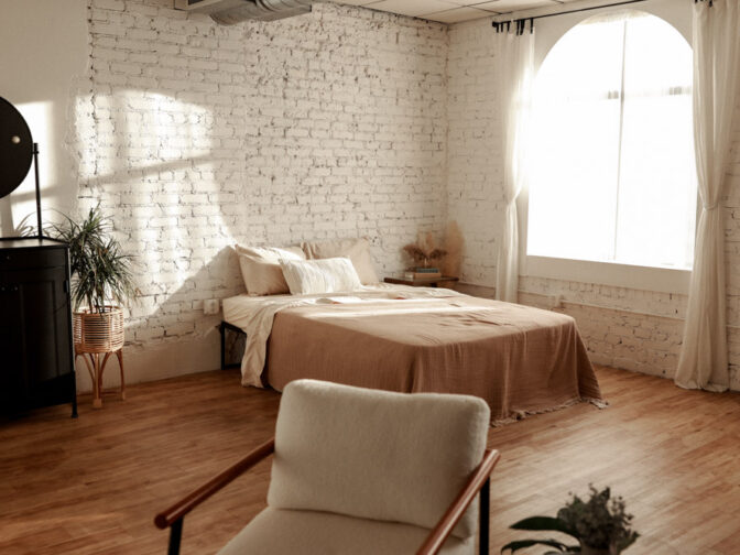 Cozy bedroom with a rustic brick wall and warm natural light.