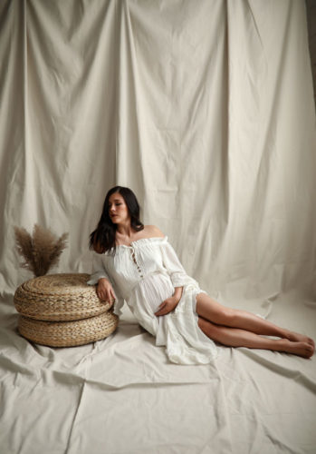 pregnant woman posing in white flowing dress.