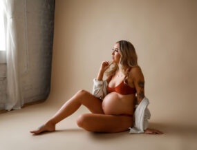 Pregnant woman posing in lingerie and button up stop.