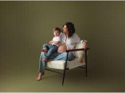 Pregnant woman sitting on chair with baby.